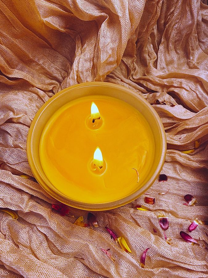 Two-wick beeswax candle lit in a frosted glass jar
