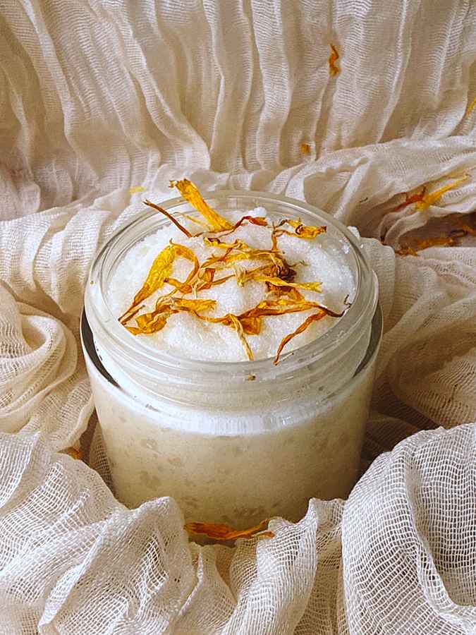 Saanjh Glow sugar scrub in a glass jar topped with calendula petals