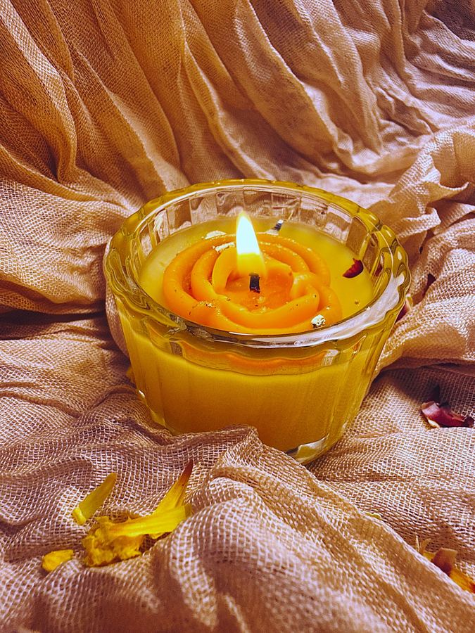 Fluted glass votive topped with an orange beeswax jalebi
